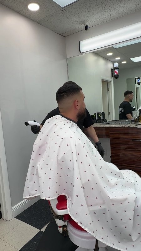 A barber working a clean fade on a seated, caped client at Florida Fresh Cuts
