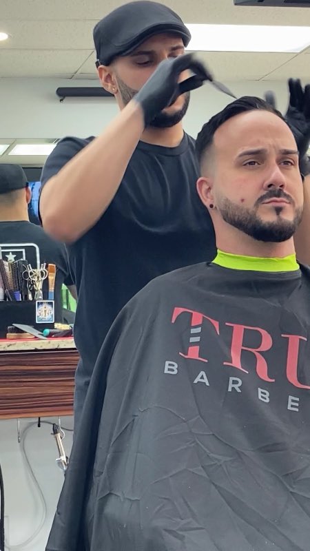 A barber styling and finishing a client's haircut at Florida Fresh Cuts